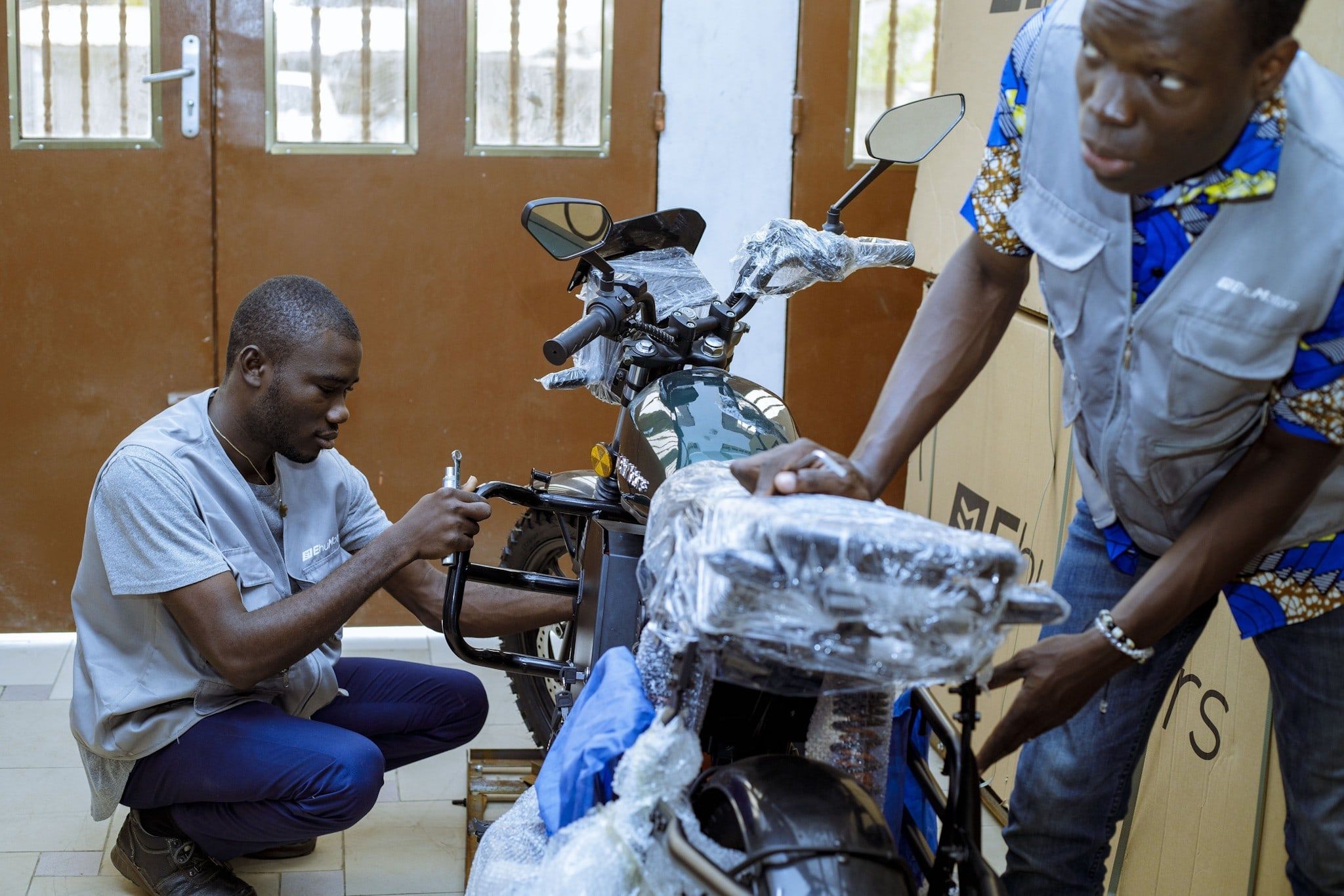 Deux techniciens Ehu préparent une moto neuve à l'atelier de Cotonou.